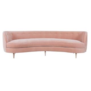 A curved pink velvet couch