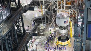 A white cylinder with an american flag is lowered into a fitting hole on a raised metal platform.