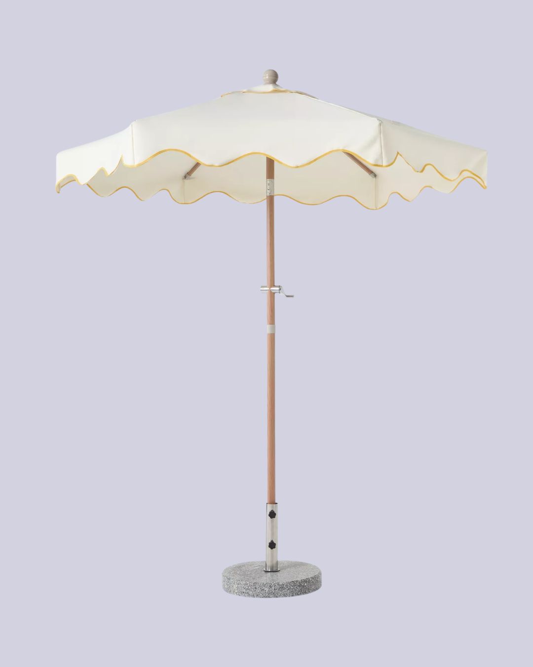 A white scalloped parasols with yellow hem, a wooden stem, and a stone base, against a pale lilac background.