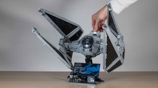 Lego TIE Interceptor, 3/4 view on a neutral background with hand lifting up cockpit hatch