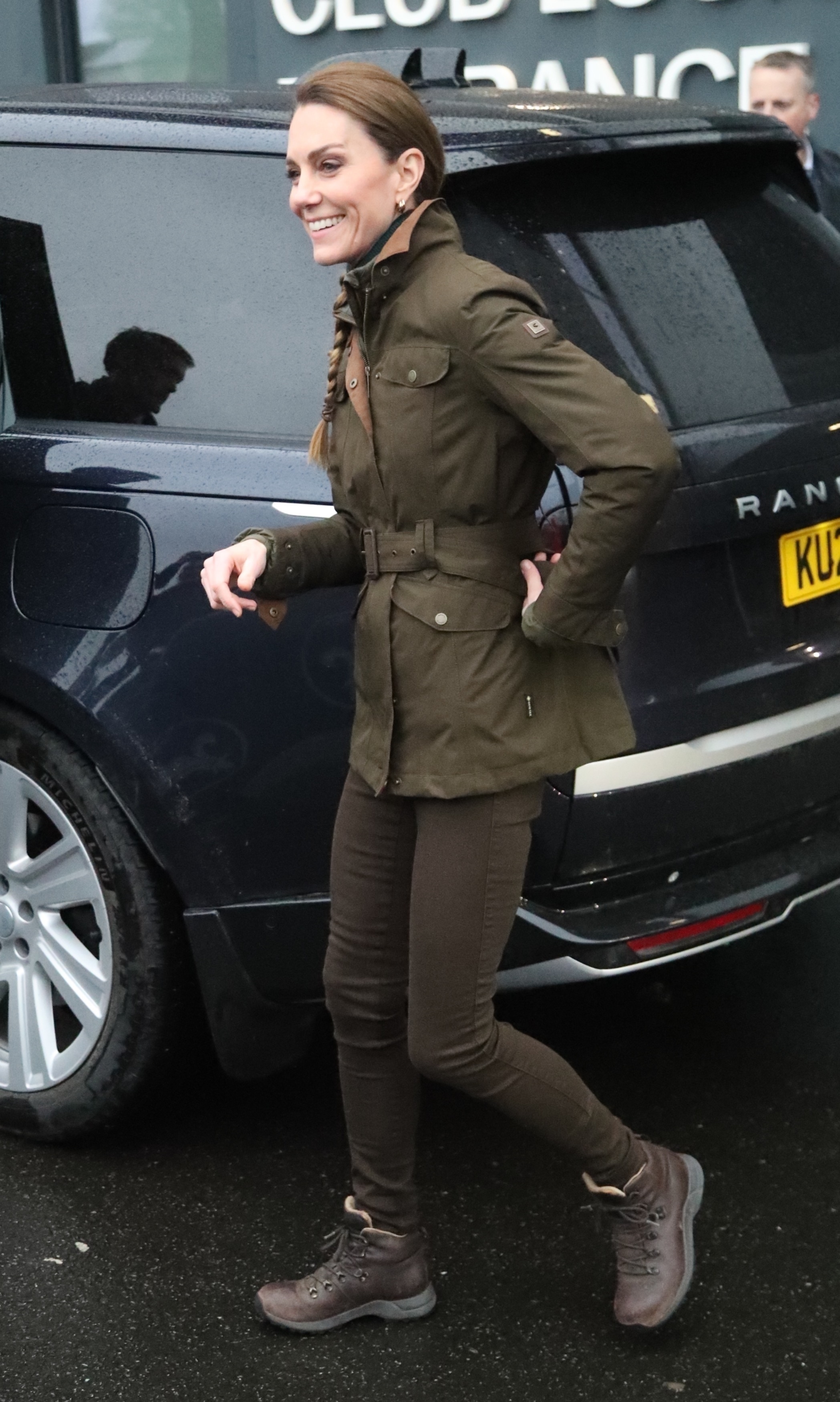 Kate Middleton wears a army green coat, brown skinny jeans, and brown boots.