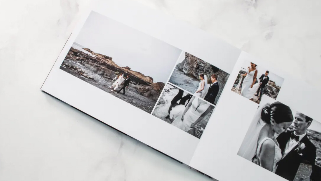 A wedding photo album open on a marble surface, showcasing couples on a rocky beach, capturing romantic moments in various frames