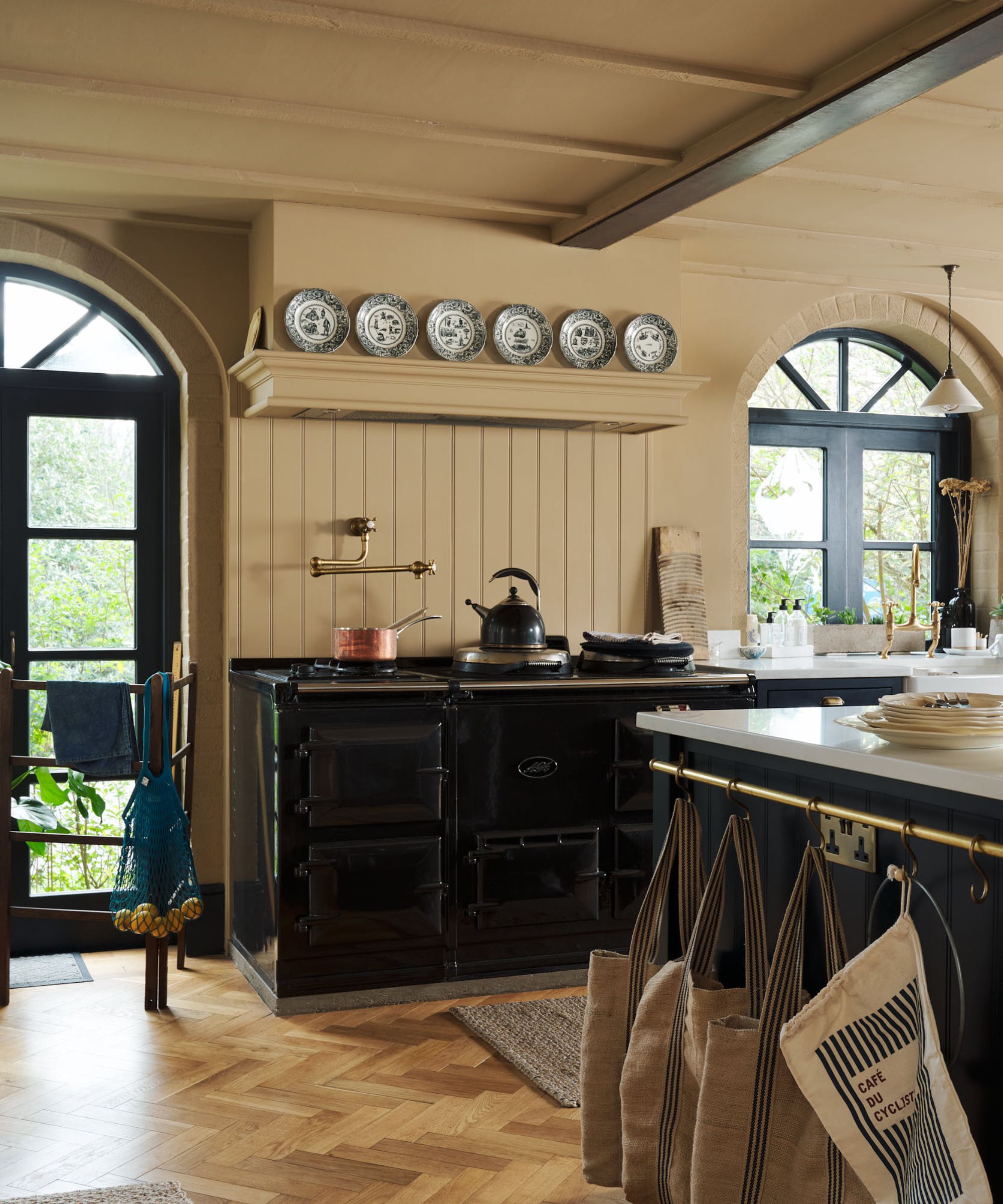 A traditional kitchen with a black range cooker and a paneled range hood decorated with plates