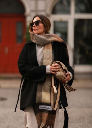 woman wearing sunglasses and an oversized Acne Studios scarf