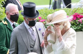 Camilla, Duchess of Cornwall adjusts her face mask as she attends Royal Ascot 2021 with Prince Charles Prince of Wales at Ascot Racecourse