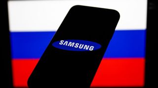 Samsung logo displayed on a phone screen and Russian flag displayed on a screen in the background