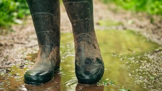 Person wearing wellington boots standing on a wet trail