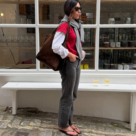 An image of a woman wearing layered t-shirt and jeans, part of spring basics outfits 2026.