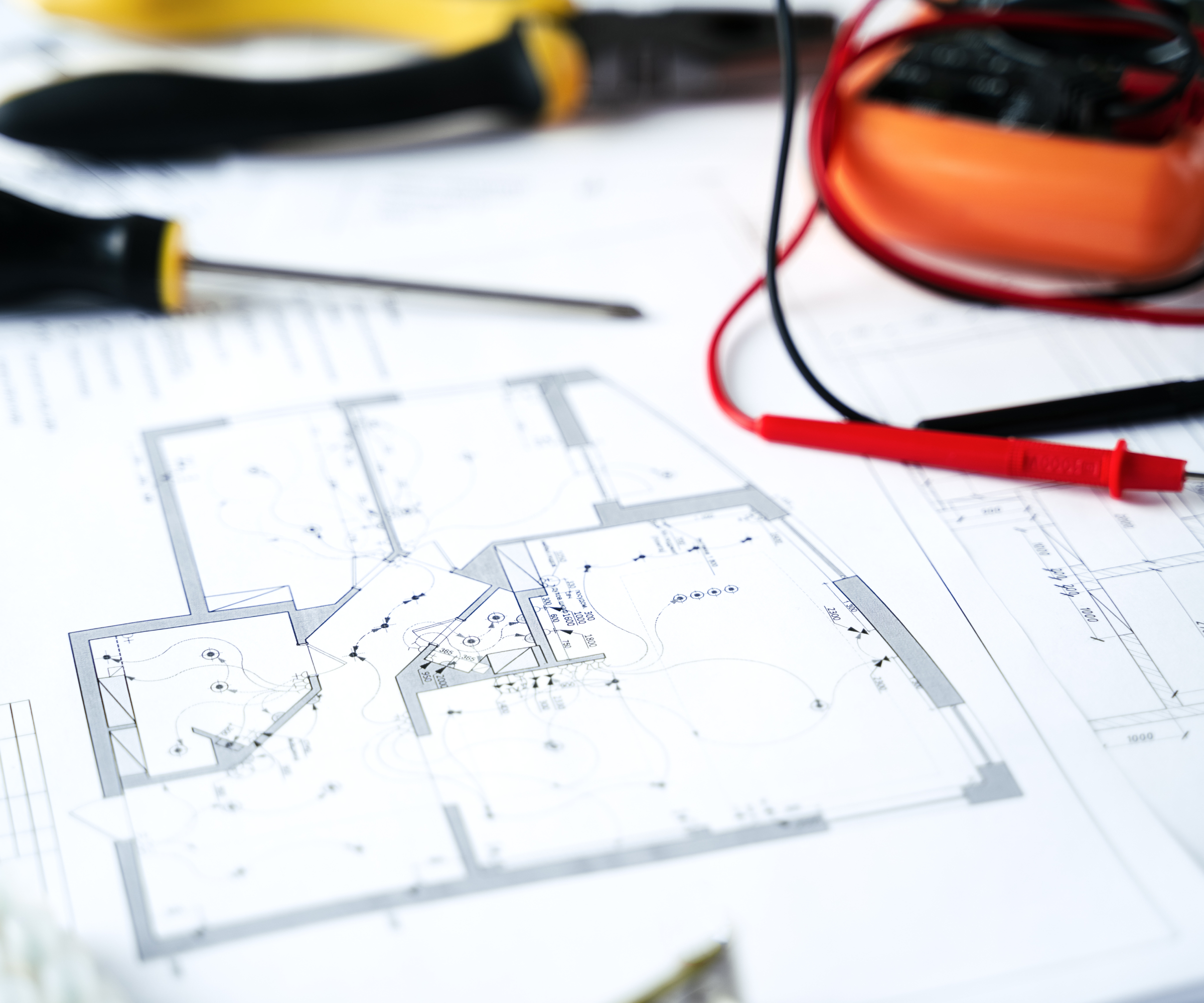 electrical plans on table with screwdriver, pliers and cable testing kit