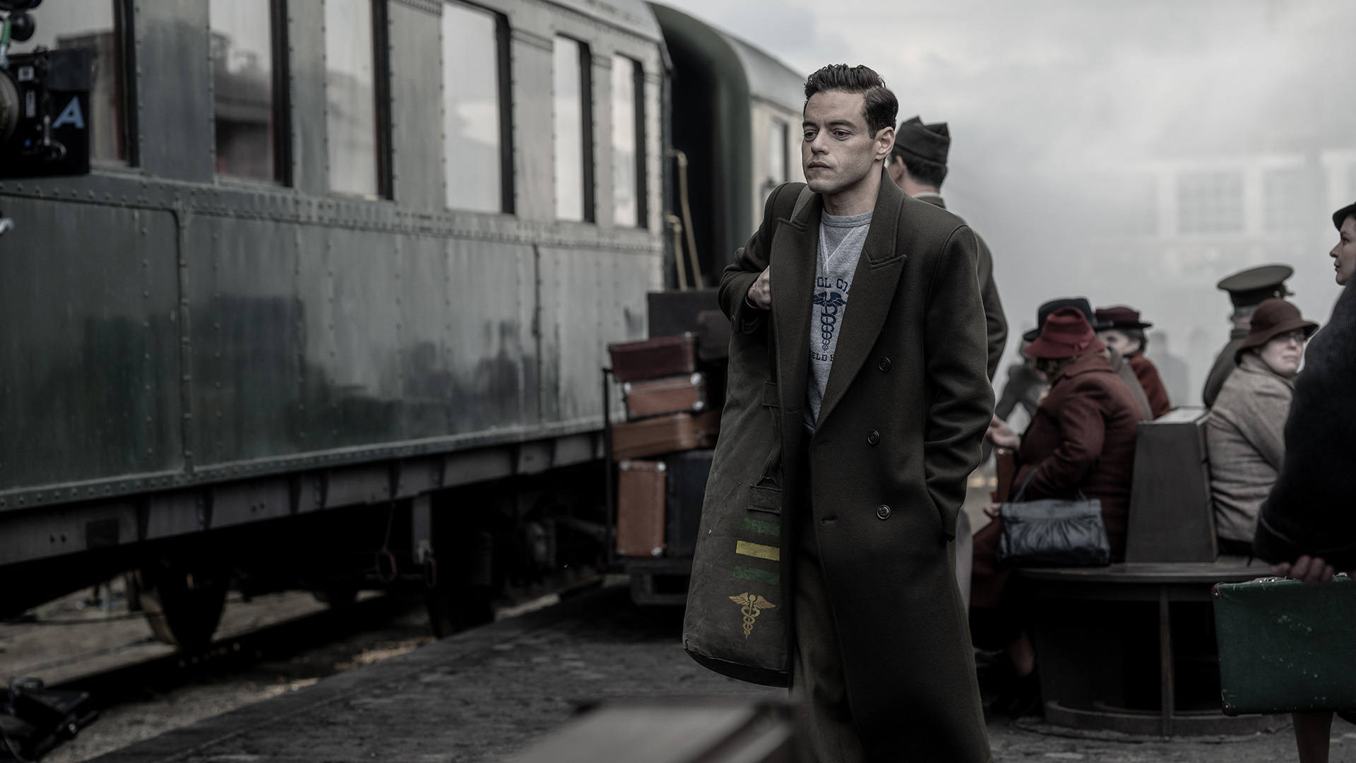 Rami Malek as Lt. Col. Douglas Kelley in Nuremberg, standing by a train.