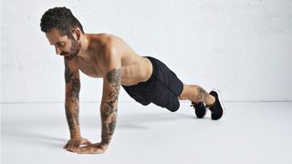 Man performing a diamond push-up in black shorts