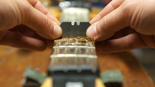 Removing grime from a bass guitar fretboard using a Stanley blade