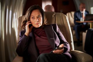 Pernilla August as The Queen in an airplane on the phone
