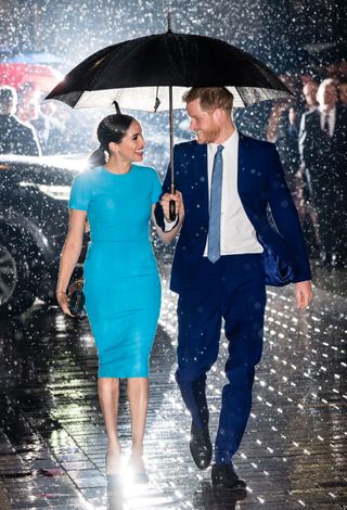 Meghan Markle and Prince Harry walking with an umbrella