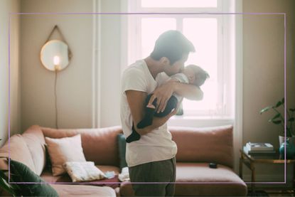 Man holding newborn baby against a bright window