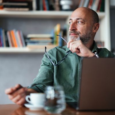 Man Working in a Home Office Seated by a Laptop