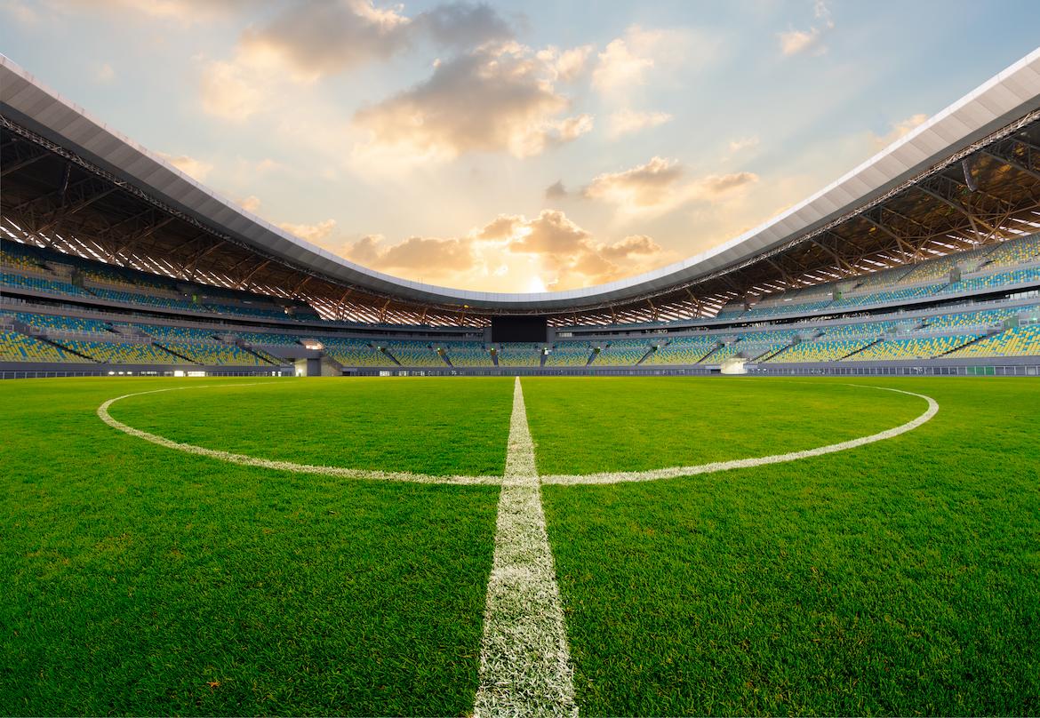 A football stadium with a cloudy sunset backdrop.