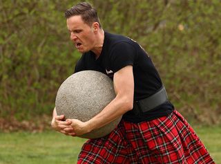 A competitor clutching a 90 kg stone weight to his chest – that's over 15 stone - duriing a Highland Games event