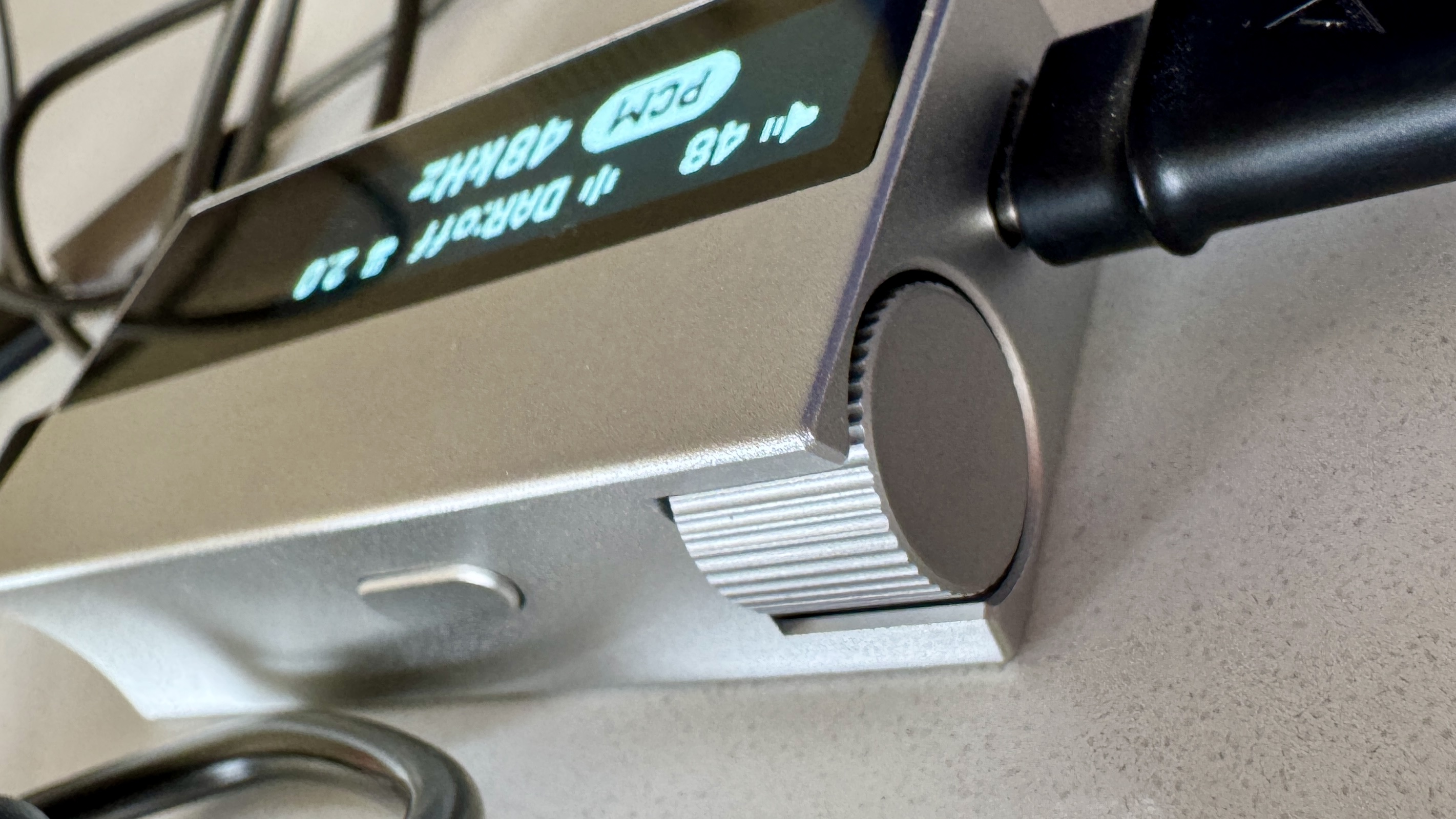 The Astell & Kern AK HC5 on a grey table, with the top plate illuminated and hooked up to Sennheiser IEMs and a FiiO digital audio player