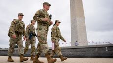 The Washington Monument is visible as National Guard troops walk along the National Mall