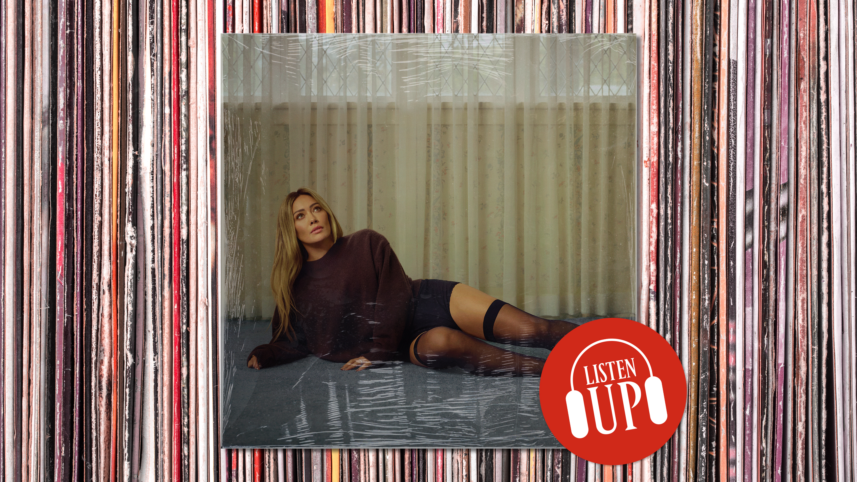 hilary duff wears a black long sleeve top as she lies on the ground in black shorts and thigh high socks on the cover of her album luck or something with the image treated with marie claire's listen up logo
