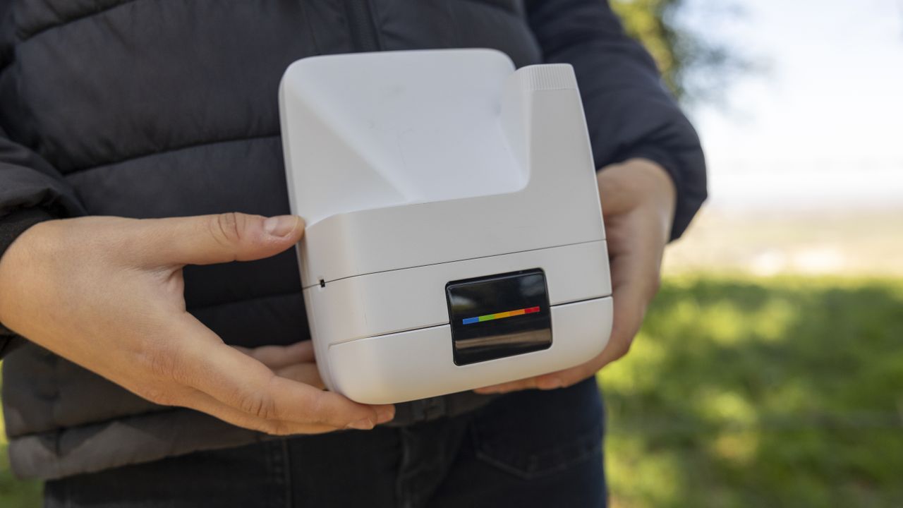 A female photographer holds the Polaroid Flip instant camera in a sunny field