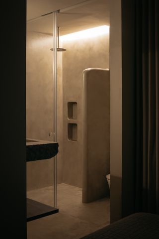 A bathroom with microcement walls, and a half wall hiding a WC