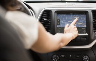 Mixed Race woman using touch screen navigation map in car