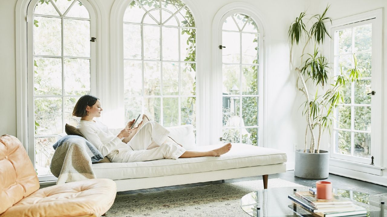 A rich woman sits on a couch.