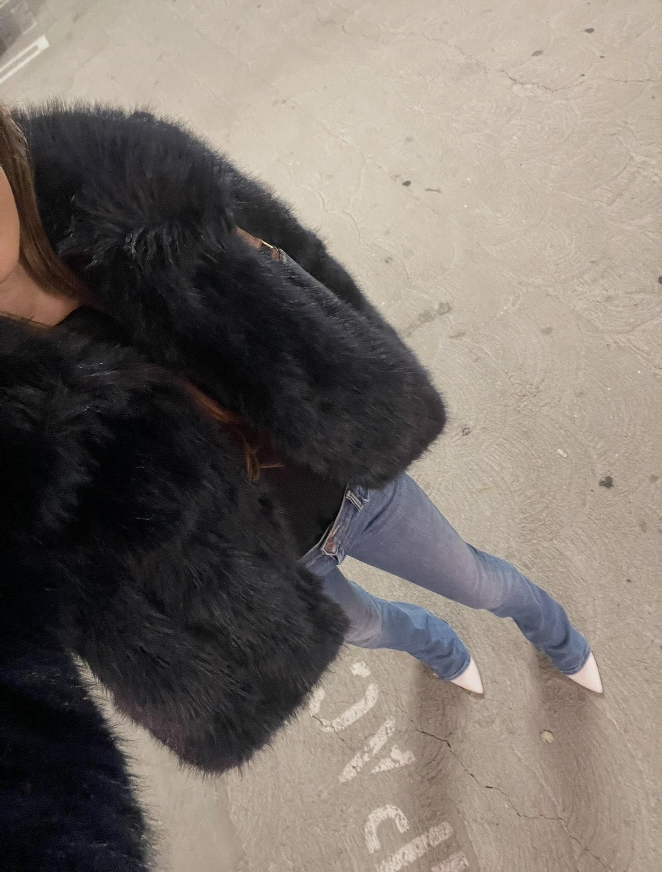 Woman wearing bootcut jeans with white pointed-toe heels.