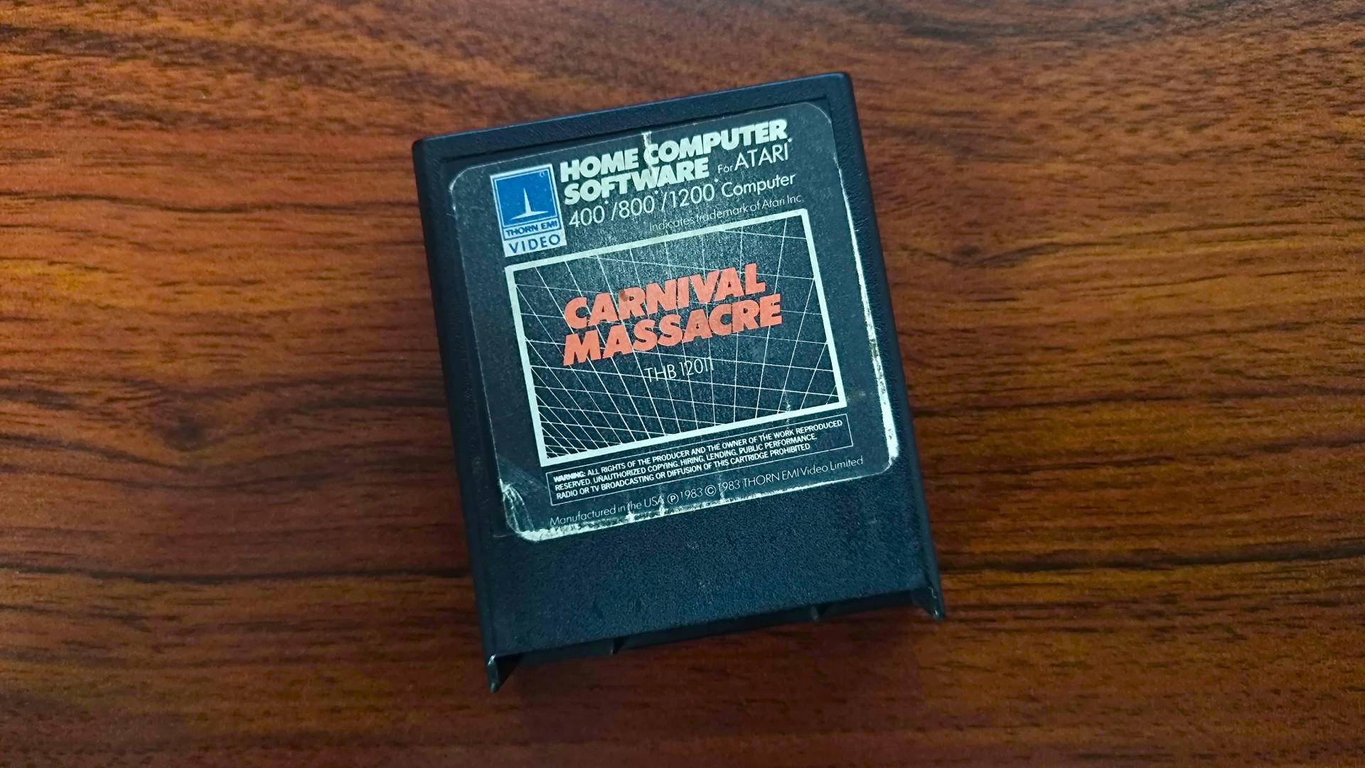 Carnival Massacre Atari cartridge on woodgrain desk.