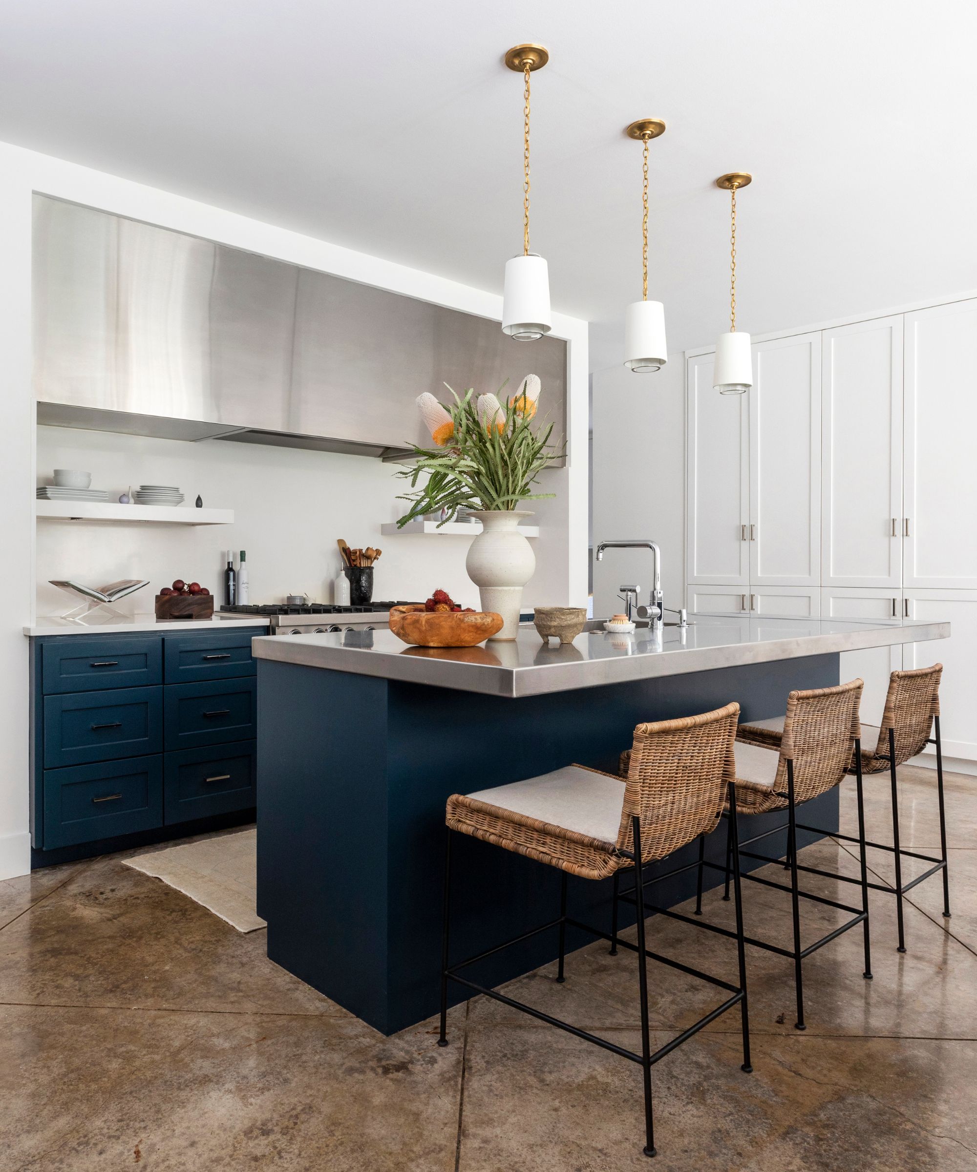 A modern kitchen with blue cabinets, stainless steel finishes, and a painted backsplash