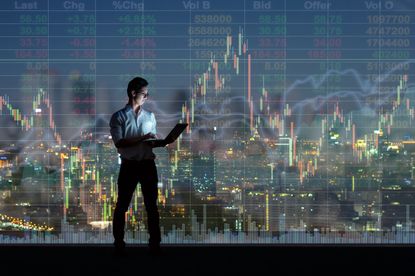 Asian businessman standing and using the smart mobile phone showing the Stock market chart over the cityscape background at night time, Businesstechnology and trading concept