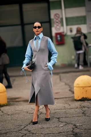 a guest at Milan Fashion Week wearing a button down shirt with a tie under a dress