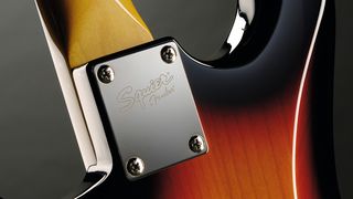 Close-up of the neck plate on a Squier electric guitar