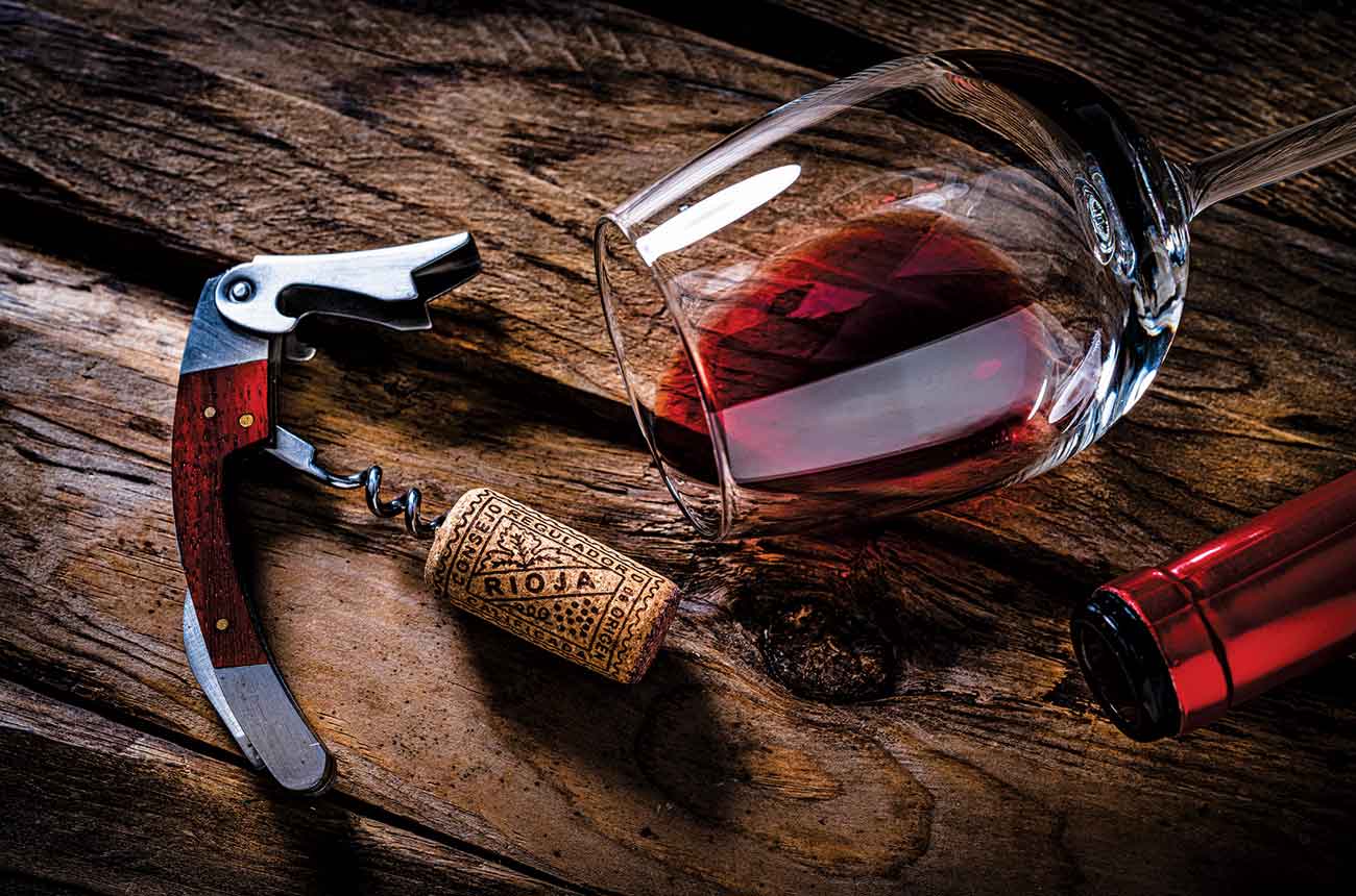 Glass of red Rioja on its side and a corkscrew