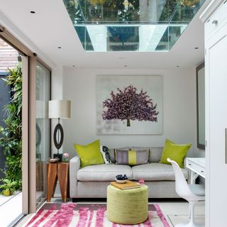 A modern living room with glass ceiling pane and pink striped rug