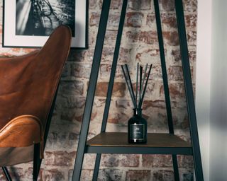 a black diffuser sat on a dark wooden table in a red brick room