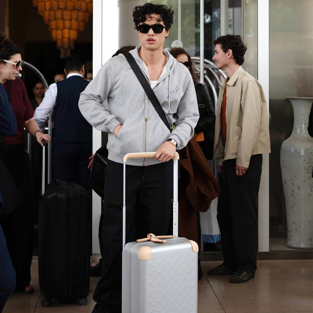 Charles Melton with a Louis Vuitton suitcase