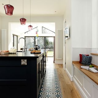 kitchen area with wooden floor and white wall and black counter