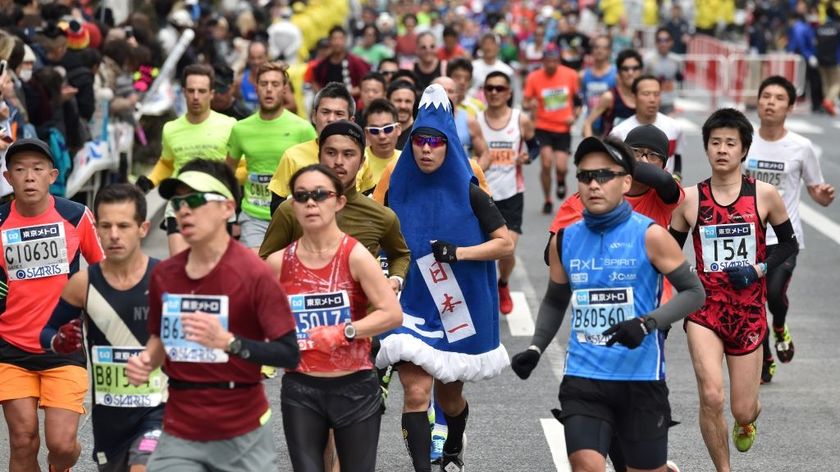 A runner (C) wearing a Mt. Fuji costume passes through the Ginza shopping district during the Tokyo Marathon in Tokyo on February 25, 2018. / AFP PHOTO / Kazuhiro NOGI (Photo credit should read KAZUHIRO NOGI/AFP via Getty Images)