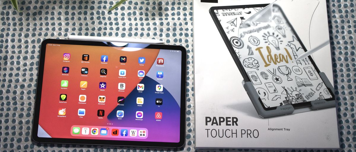 An iPad tablet with a PaperTouch Pro screen protector sitting next to the screen protector packaging.