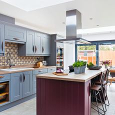 Modern open plan kitchen diner with kitchen island and extractor hood, retro handles on light blue kitchen units