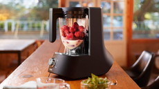 The Tiger 45 Degree Diagonal-Blade Blender on a wooden table, filled with frozen strawberries and milk ready to blend