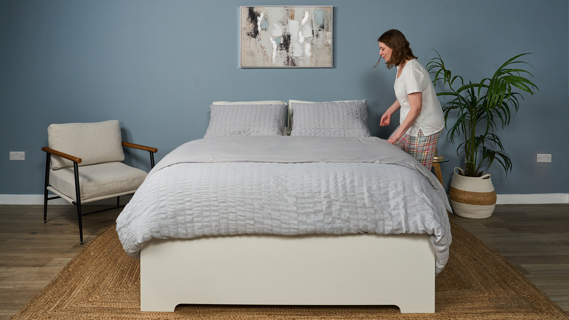 A woman gets ready to climb into a bed that's been dressed in sheets 