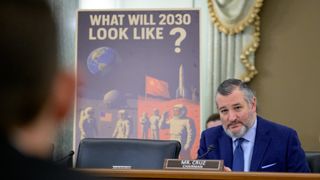 a man in a blue suit behind a microphone in a wood paneled room