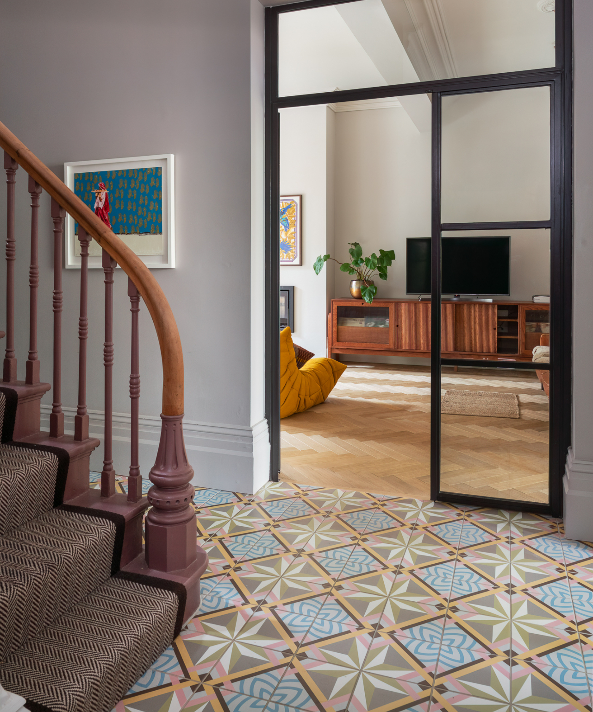 hallway with tiled floor, stair runner on wooden stairs and leading to living room with wooden floor