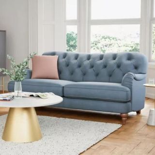 A light blue sofa surrounded by white furniture