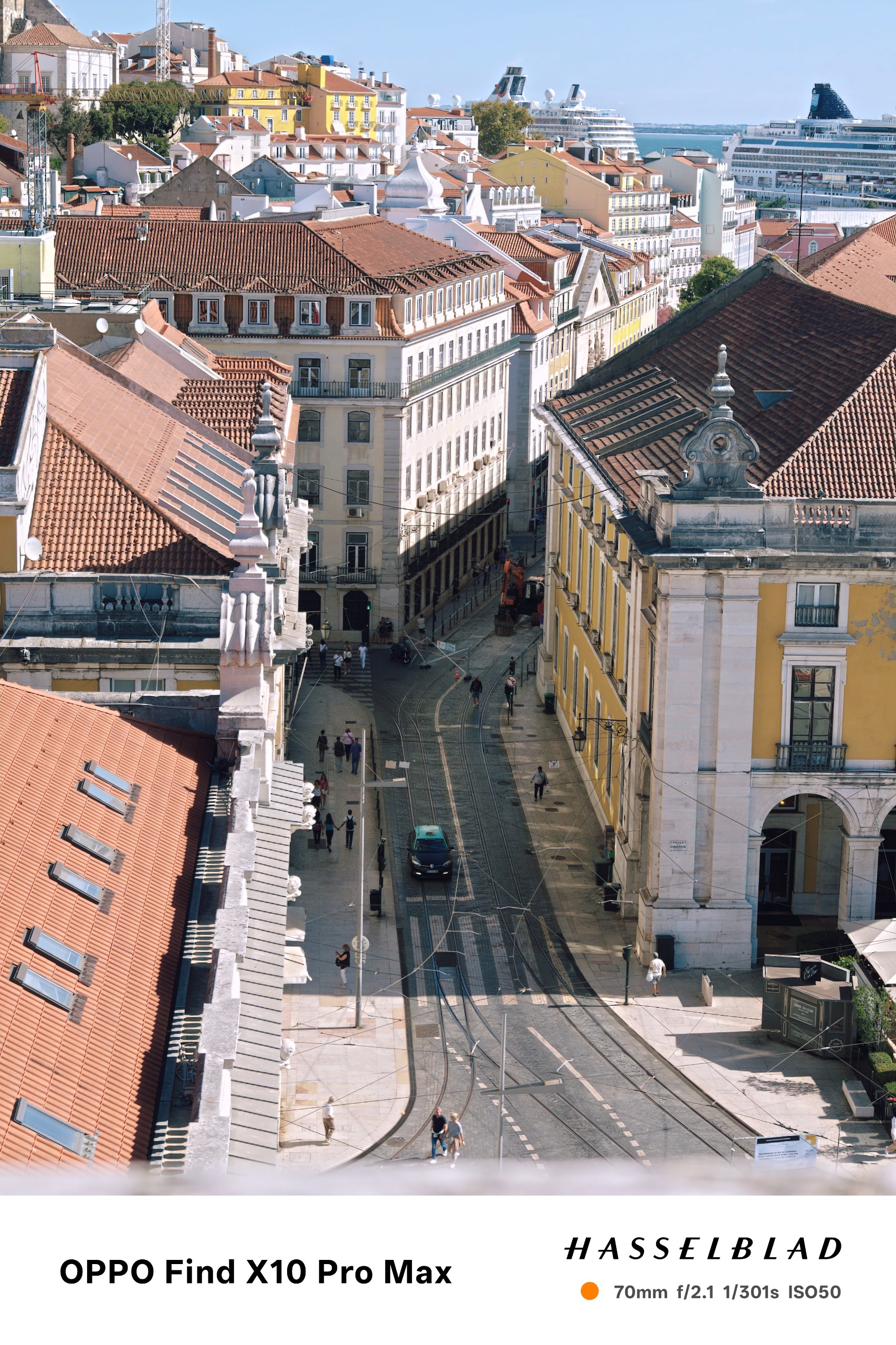 Elevated city view of Lisbon streets, tiled rooftops and cruise ships in the distance.