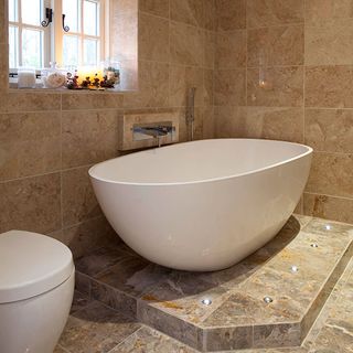 bathroom with bathtub honey toned marble wall and floor and window